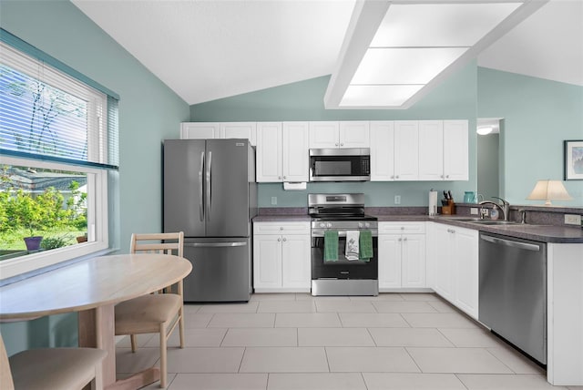 kitchen with white cabinets, stainless steel appliances, and vaulted ceiling