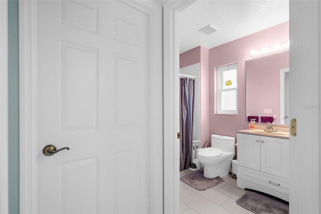 bathroom with a textured ceiling, vanity, and toilet