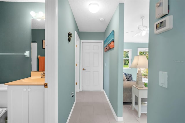 hallway with light tile patterned floors, a textured ceiling, and sink