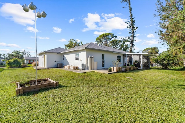 back of house featuring a sunroom, a lawn, and central AC