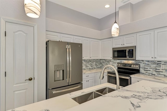 kitchen featuring backsplash, white cabinetry, hanging light fixtures, and appliances with stainless steel finishes