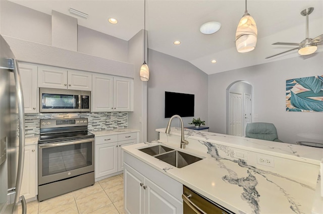 kitchen with pendant lighting, lofted ceiling, white cabinets, sink, and appliances with stainless steel finishes