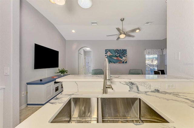 kitchen featuring sink, vaulted ceiling, ceiling fan, light stone countertops, and kitchen peninsula