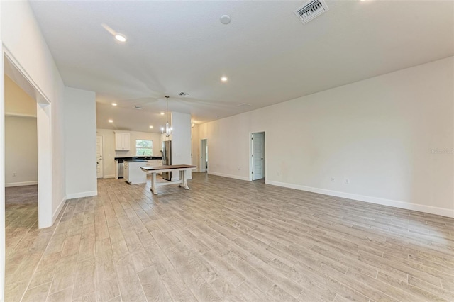 unfurnished living room featuring light hardwood / wood-style floors and an inviting chandelier