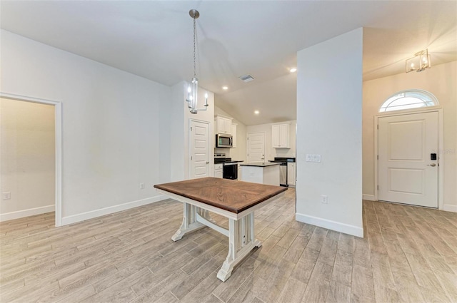 kitchen featuring stainless steel appliances, light hardwood / wood-style floors, vaulted ceiling, decorative light fixtures, and white cabinets