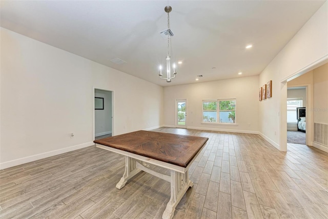 unfurnished dining area featuring a chandelier and light wood-type flooring