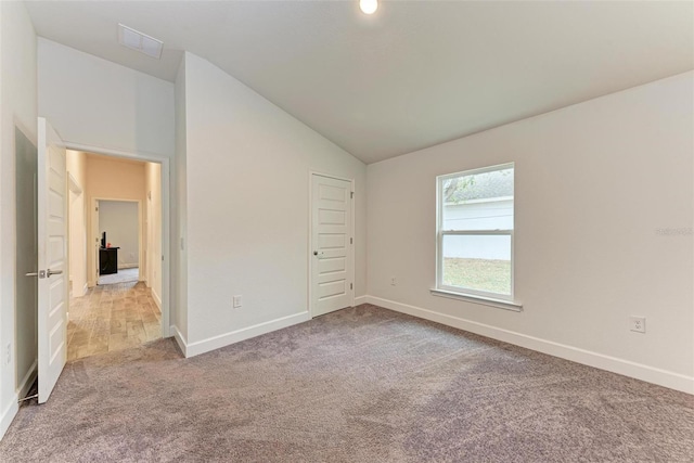 unfurnished bedroom featuring a closet, light colored carpet, and lofted ceiling