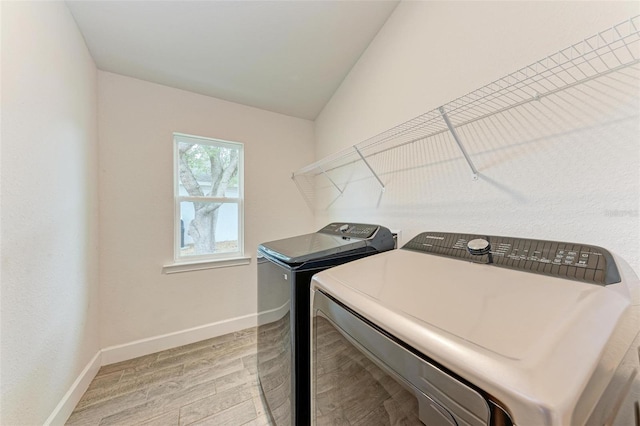 washroom with light hardwood / wood-style flooring and washer and dryer