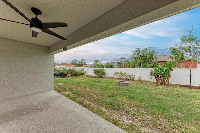 view of yard featuring ceiling fan and a fire pit