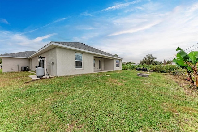 rear view of property featuring a yard and cooling unit