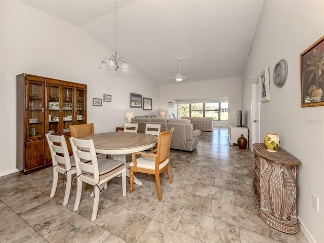 dining room featuring ceiling fan with notable chandelier and high vaulted ceiling