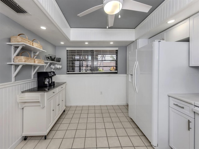 kitchen with ceiling fan, white fridge with ice dispenser, light tile patterned floors, and white cabinets