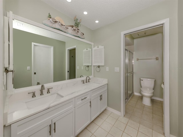 bathroom featuring tile patterned flooring, vanity, toilet, a shower with door, and a textured ceiling