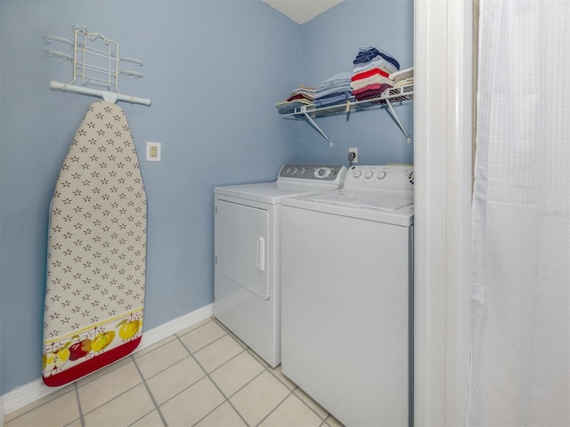 clothes washing area featuring washer and clothes dryer and light tile patterned flooring