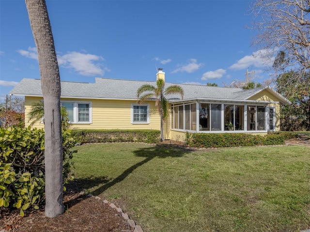 back of property with a sunroom and a yard