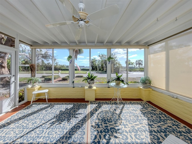 unfurnished sunroom featuring beam ceiling, ceiling fan, and a healthy amount of sunlight