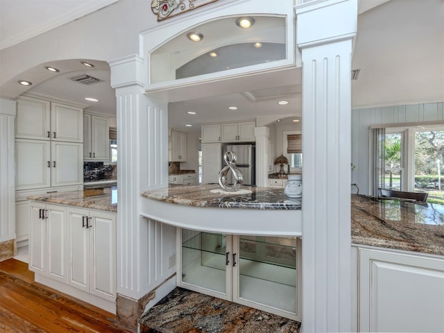 kitchen featuring stainless steel refrigerator, white cabinetry, dark wood-type flooring, decorative columns, and dark stone countertops