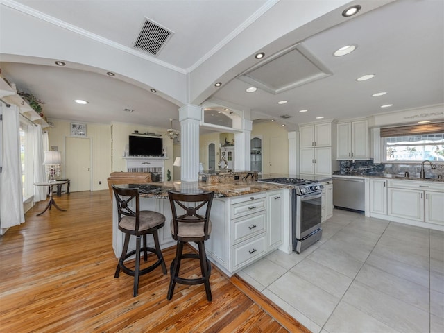 kitchen with white cabinets, a kitchen island, dark stone countertops, and appliances with stainless steel finishes