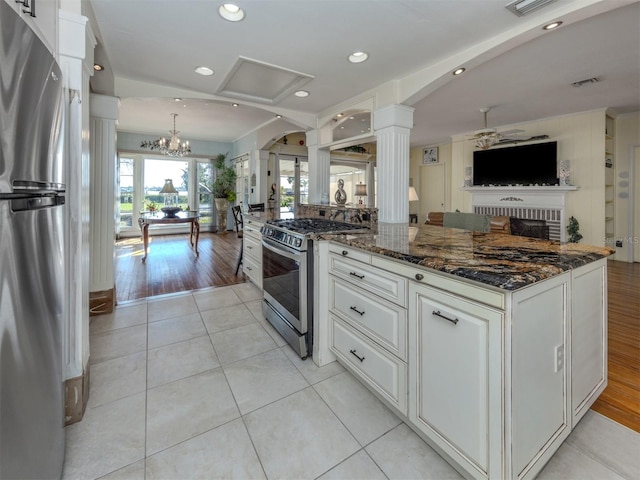 kitchen featuring white cabinetry, light wood-type flooring, stainless steel appliances, and dark stone counters