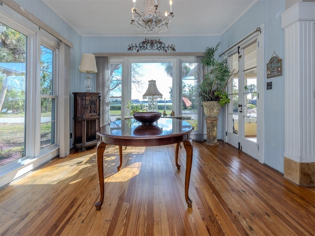 dining room featuring french doors, wood-type flooring, crown molding, and an inviting chandelier