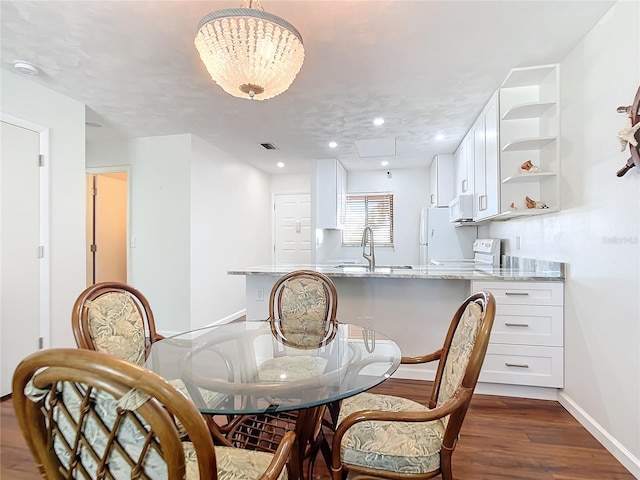 dining space with dark hardwood / wood-style flooring, sink, and a chandelier