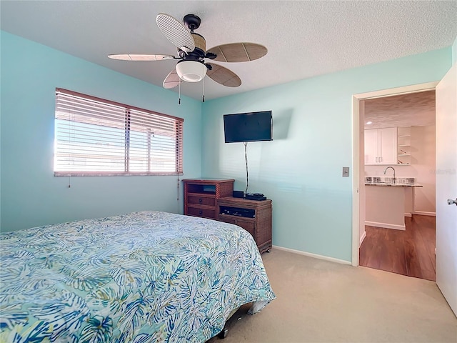 carpeted bedroom with ceiling fan, sink, and a textured ceiling