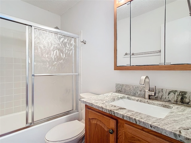 full bathroom featuring vanity, enclosed tub / shower combo, a textured ceiling, and toilet