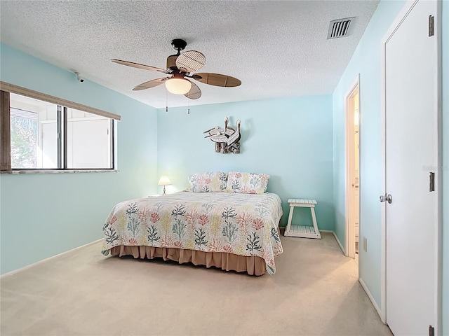 bedroom featuring a textured ceiling, light colored carpet, and ceiling fan