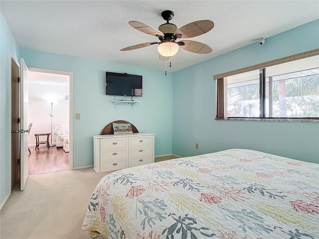 carpeted bedroom with ceiling fan and a textured ceiling