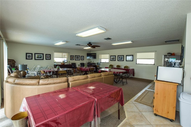 living room featuring ceiling fan, light tile patterned floors, and a textured ceiling