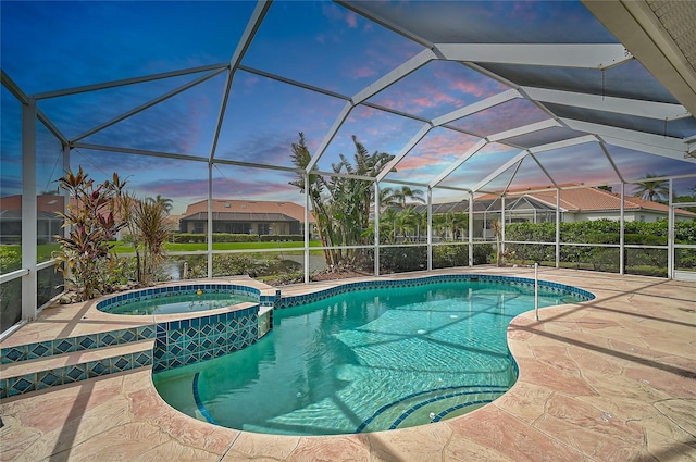 pool at dusk with a lanai, a patio area, and an in ground hot tub