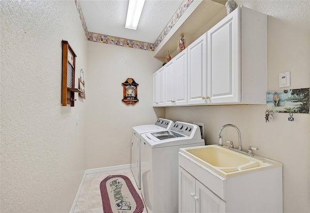 laundry area with cabinets, light tile patterned floors, a textured ceiling, and washer and clothes dryer