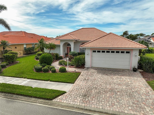 mediterranean / spanish house featuring a garage and a front yard