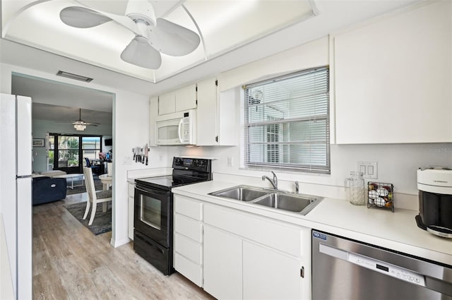 kitchen featuring light wood-type flooring, white appliances, a raised ceiling, sink, and white cabinetry