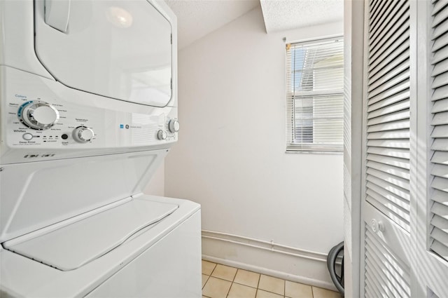 washroom featuring light tile patterned floors, a textured ceiling, and stacked washer / dryer