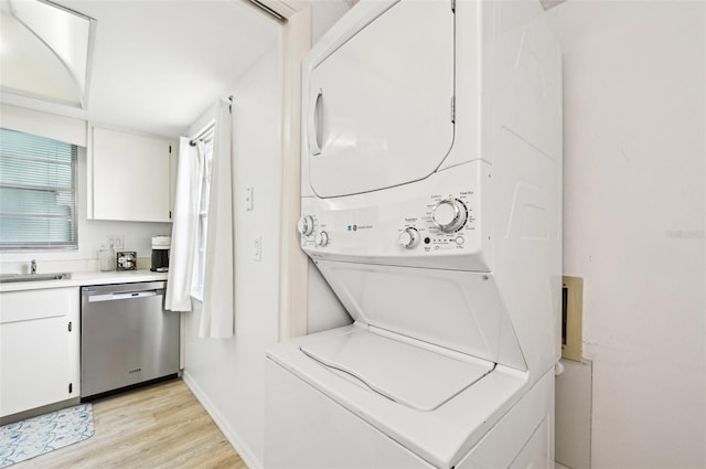 laundry area with light hardwood / wood-style floors and stacked washer / dryer