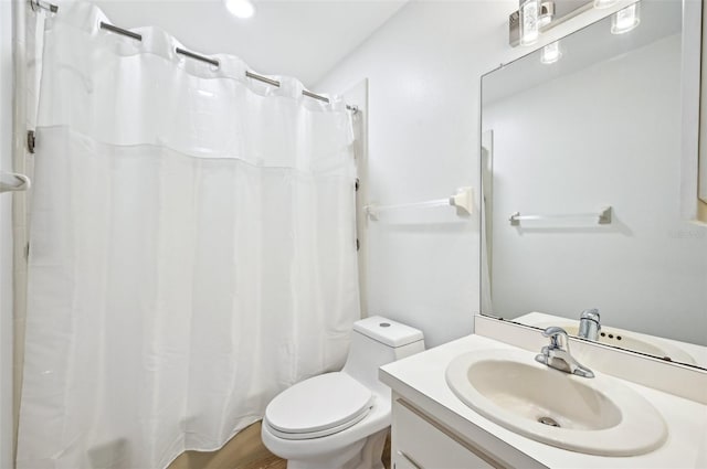 bathroom with walk in shower, vanity, and toilet