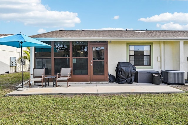 back of property with central AC unit, a patio, and a lawn