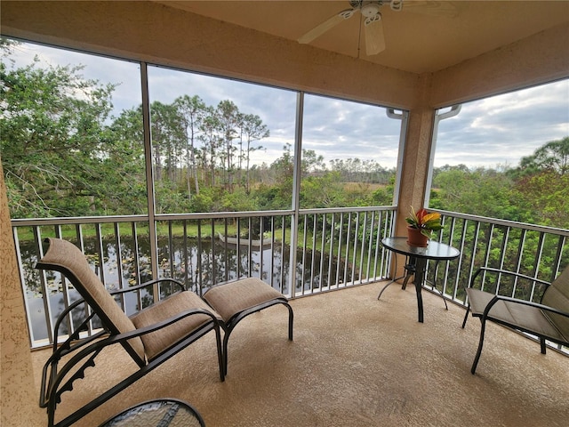 sunroom featuring ceiling fan and a water view