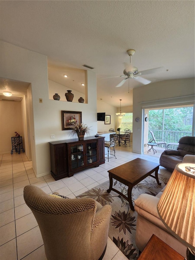 tiled living room featuring ceiling fan, vaulted ceiling, and a textured ceiling