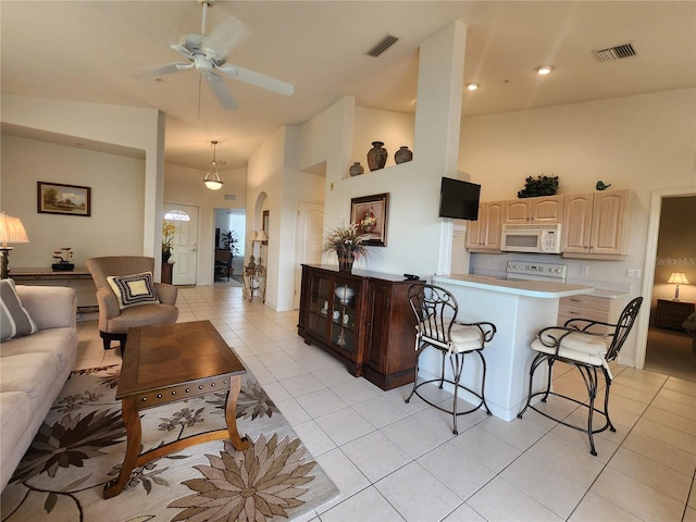 kitchen featuring light tile patterned floors, a breakfast bar area, ceiling fan, electric range oven, and a towering ceiling