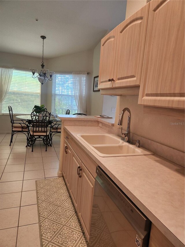 kitchen featuring light brown cabinetry, sink, decorative light fixtures, light tile patterned floors, and black dishwasher