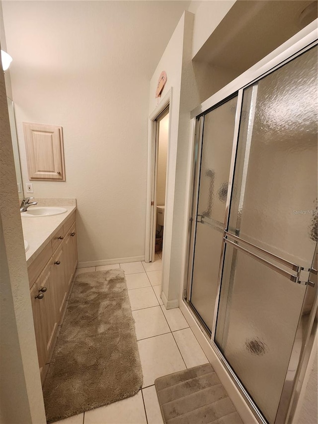 bathroom featuring vanity, a shower with door, tile patterned floors, and toilet