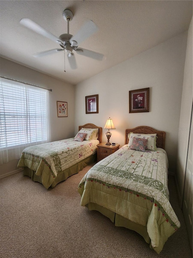 carpeted bedroom featuring ceiling fan and a textured ceiling