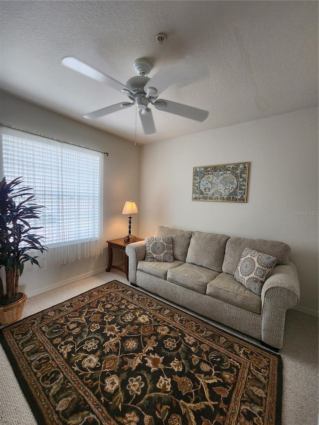 carpeted living room featuring ceiling fan and a textured ceiling