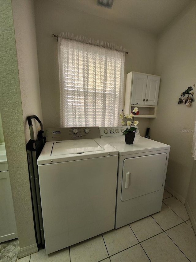 laundry room with cabinets, light tile patterned floors, and independent washer and dryer