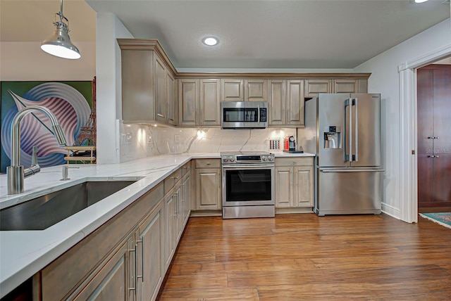 kitchen featuring pendant lighting, sink, decorative backsplash, appliances with stainless steel finishes, and light hardwood / wood-style floors