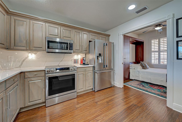 kitchen featuring decorative backsplash, appliances with stainless steel finishes, light wood-type flooring, and cream cabinetry