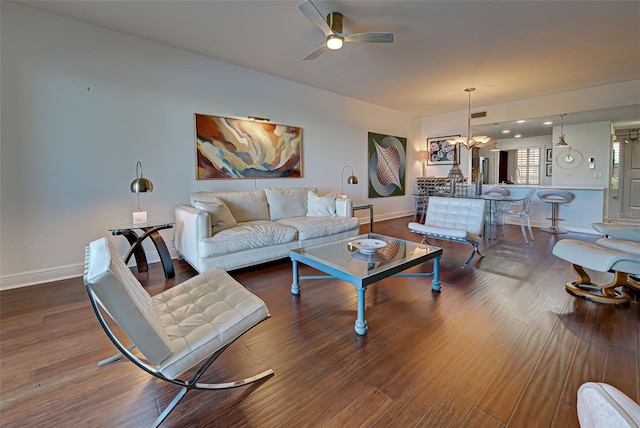 living room featuring ceiling fan with notable chandelier and dark wood-type flooring