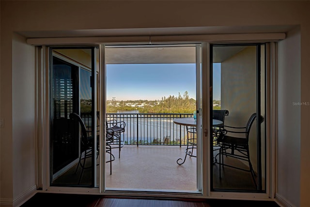 doorway to outside with hardwood / wood-style floors and a water view